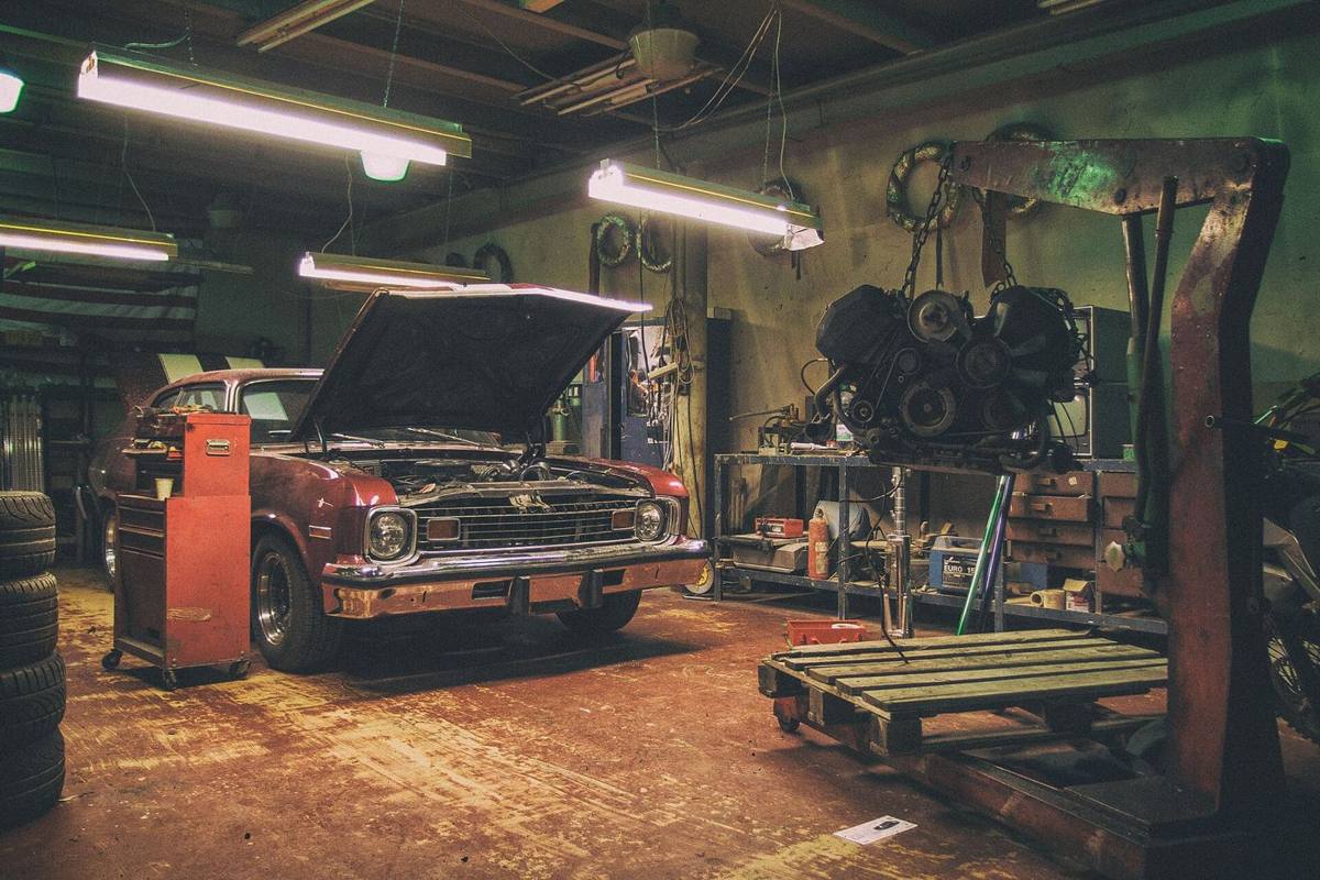 A car in a garage repair bay with its hood open