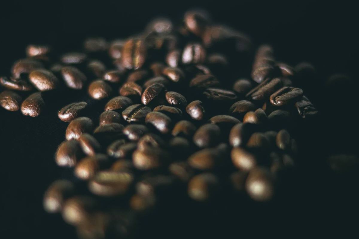 Roasted coffee beans scattered on a dark surface